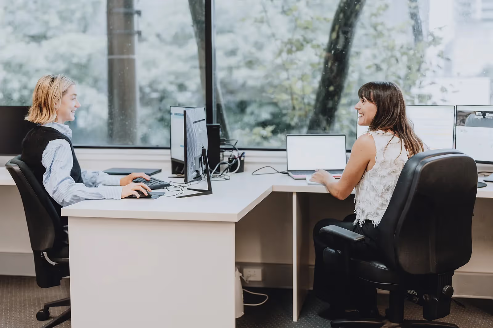 Two women sitting at office desks talking